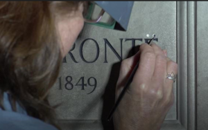 Lucy Ackland painting the dots above the" "e"